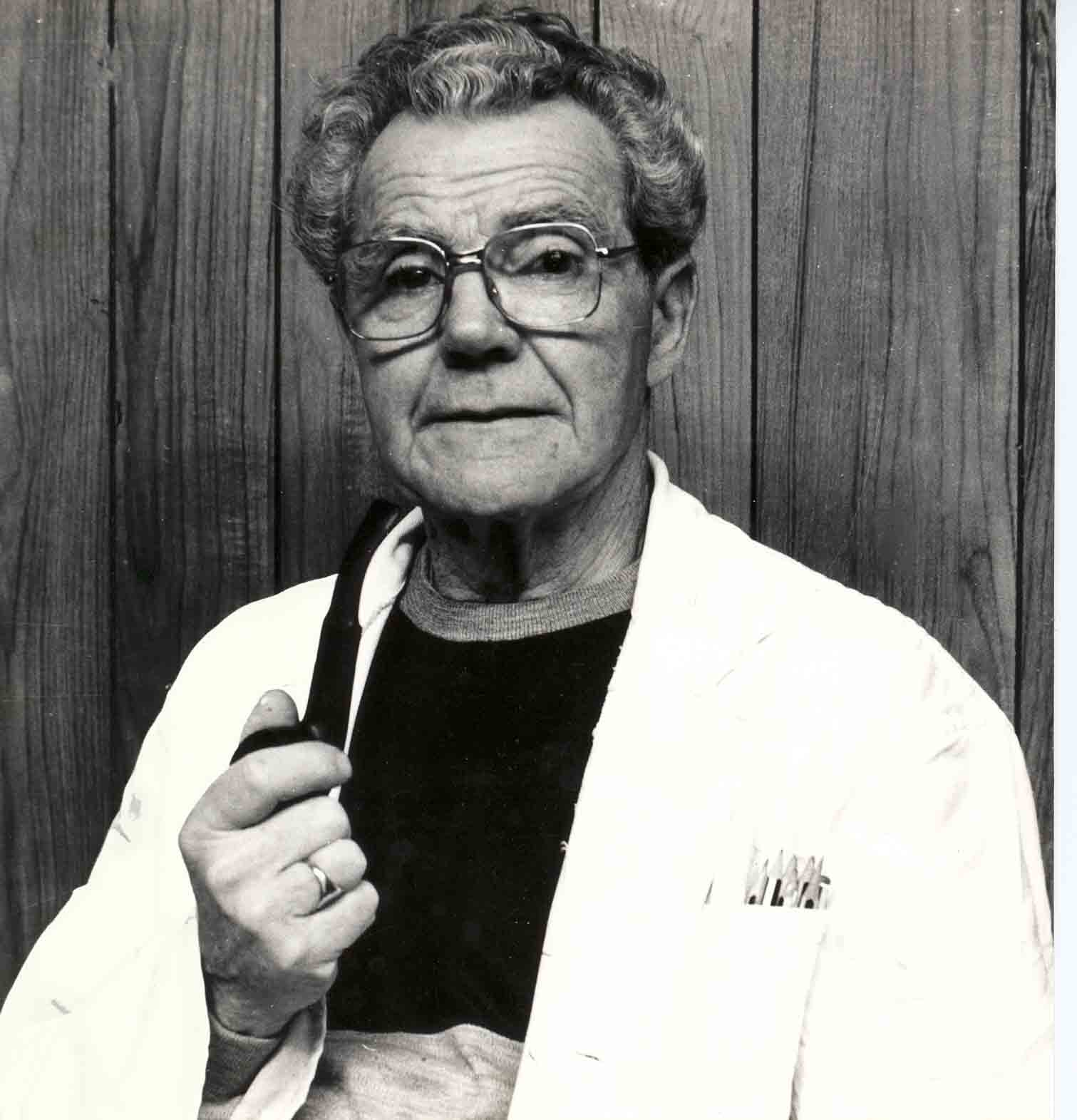  A black & white study of a carpenter, note the wood - paneling, his pipe & pencils